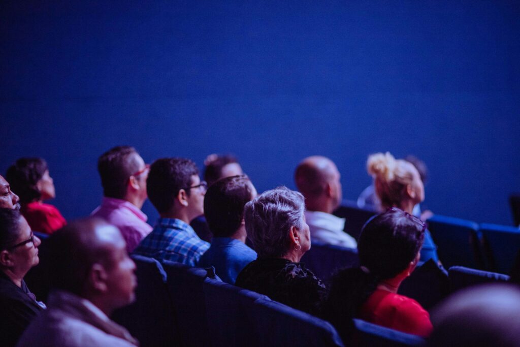 pexels-photo-2774556-2774556 An attentive group of adults seated at an indoor conference, focusing on a presentation.